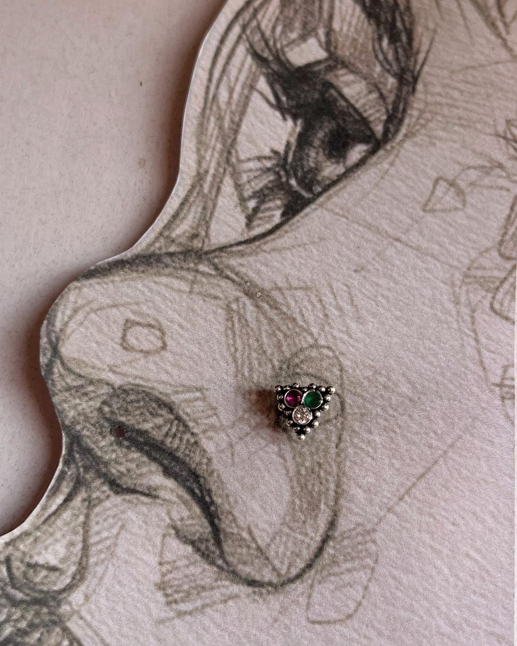 Close-up of handcrafted silver nose pin with multi-color cubic zirconia stones