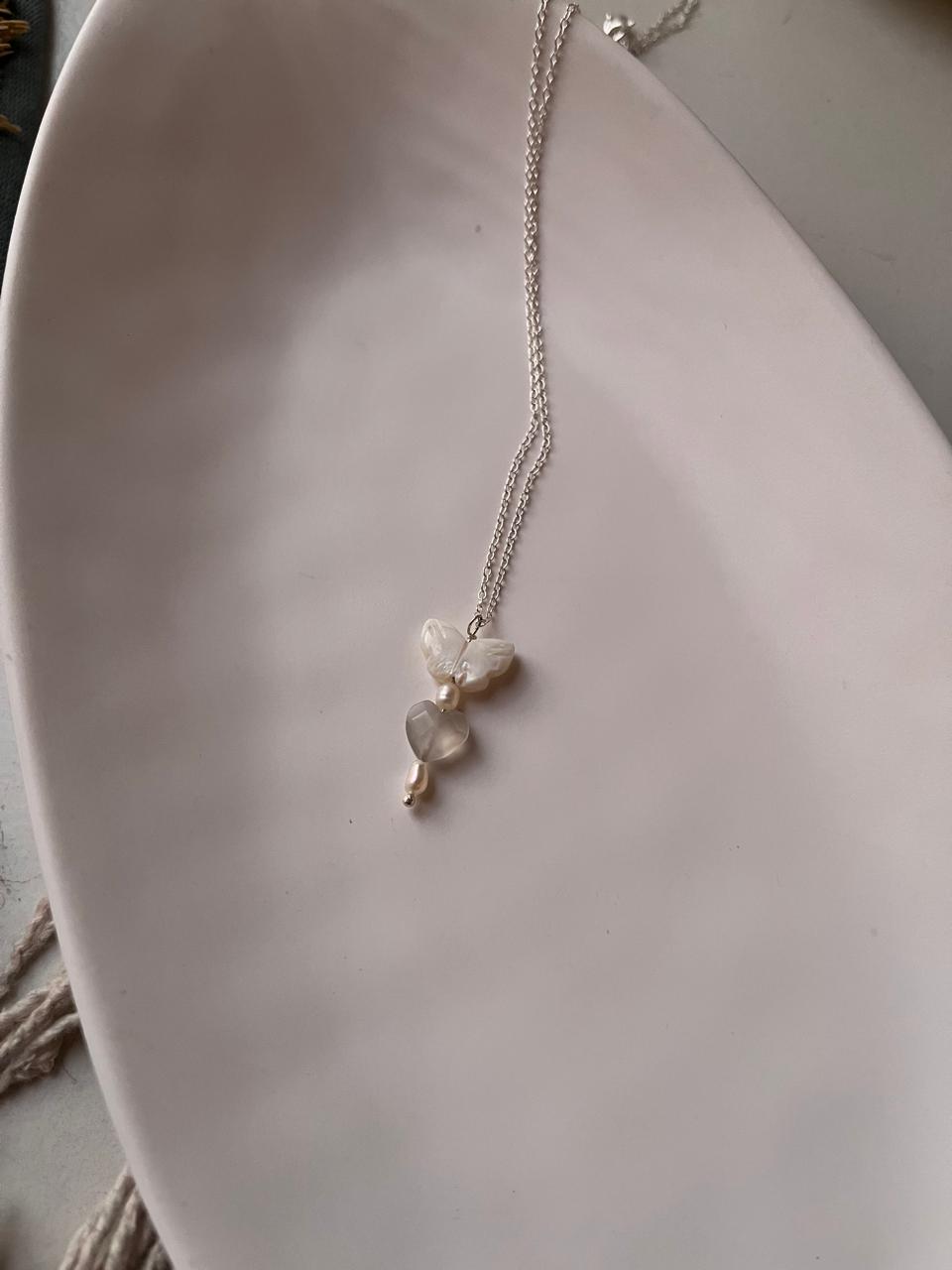 Close-up of Mother of Pearl butterfly, Grey Moonstone heart, and Fresh Water Pearls on a silver necklace