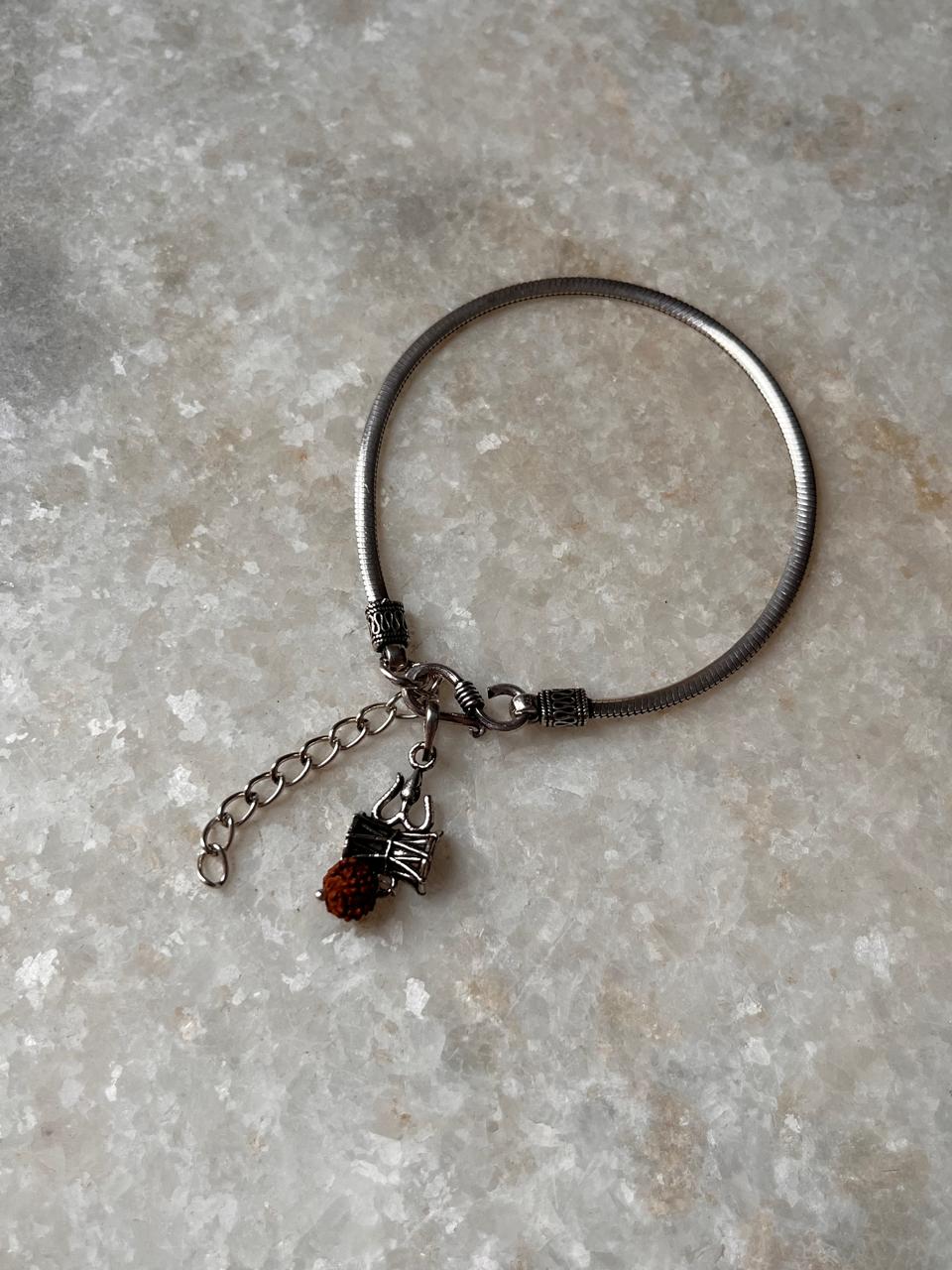 Flat Snake Antique & Trishul Damru rudraksh 925 sterling silver rakhi with chain and charm on a marble surface.