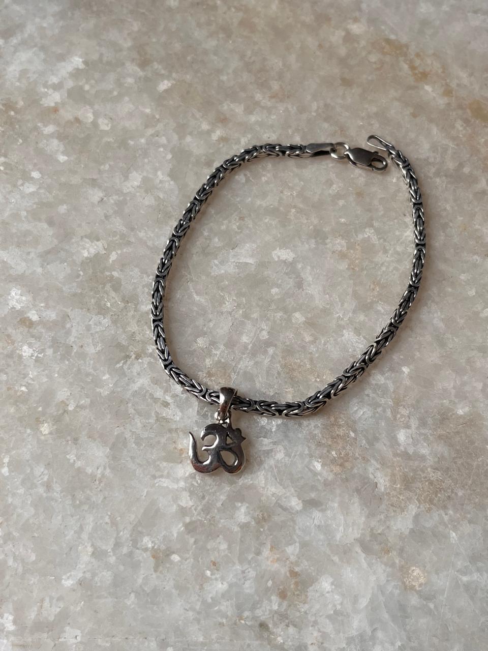 Antique patterned silver rakhi with plain Om symbol  