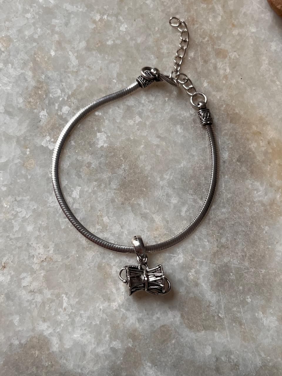 Flat Snake Antique & Medium Shiva Damru 925 Sterling Silver Rakhi on a marble surface.