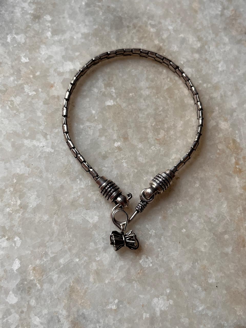 Snake patterned silver rakhi featuring Shiva’s Damru