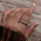 Hand wearing a Tribal Edge 925 Silver Ring, showcasing its unique design and shine on a textured surface.