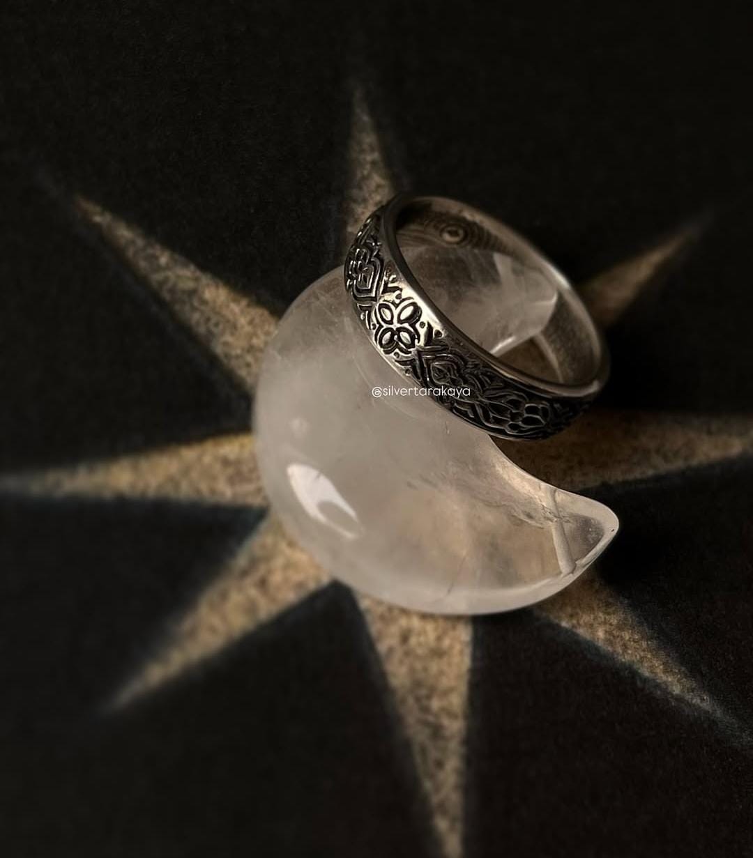Sacred Journey 925 silver ring displayed on a crescent-shaped stone, showcasing its intricate design and craftsmanship.