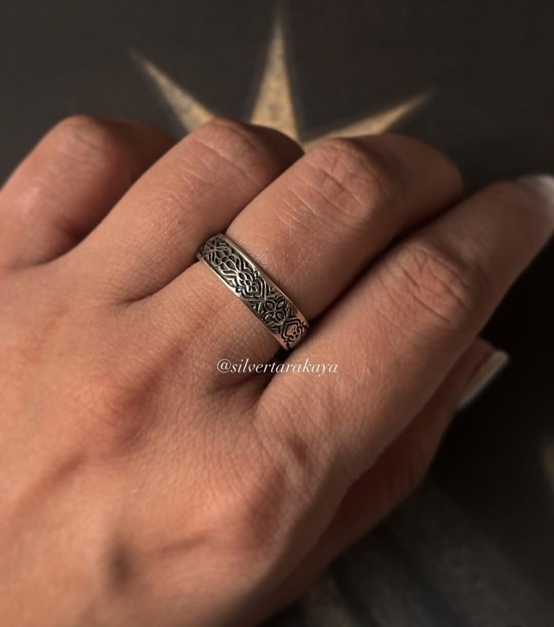 Hand wearing a decorative Sacred Journey 925 silver ring with intricate design against a star background.