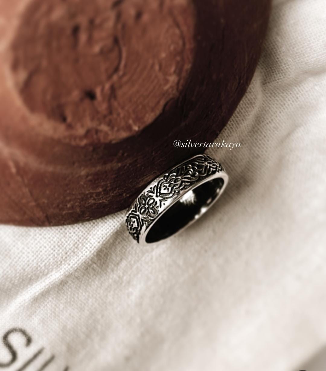 Intricately designed Sacred Journey 925 silver ring alongside a decorative pot on a soft fabric background.