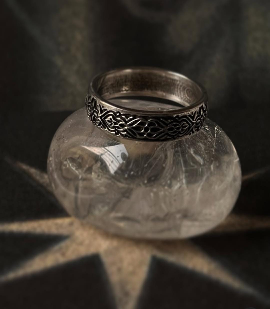 Sacred Journey 925 silver ring displayed on a decorative stone, showcasing its unique engraved design and pure silver quality.