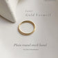 Gold vermeil plain round stack band ring on textured background, highlighting its luxury and durability.