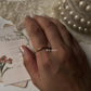 Gold vermeil plain round stack band ring on a hand, styled with floral card and pearl necklace.