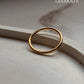 Gold vermeil plain round stack band ring on a marble surface, showcasing its elegant minimalist design.