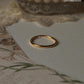 Gold vermeil plain round stack band ring on a soft surface with floral design, showcasing its shine and elegance.