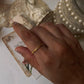 Gold vermeil thin link stack band ring worn on hand with vintage lace and pearls in background.